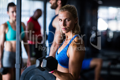 Portrait of serious woman holding dumbbell in gym