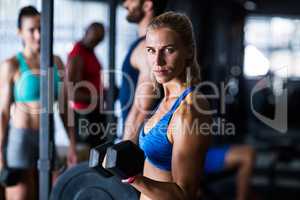 Portrait of serious woman holding dumbbell in gym