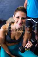 Pretty smiling woman exercising with dumbbell