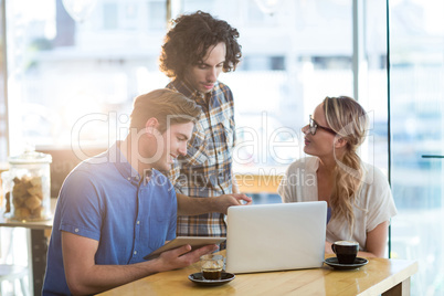 Friends using digital tablet and laptop in cafÃ?Â©