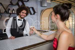 Waiter serving a cocktail to woman at bar counter