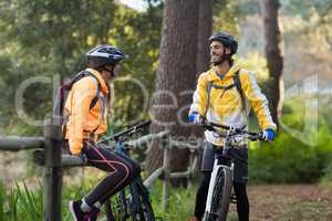 Biker couple interacting with each other in forest