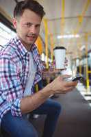 Portrait of handsome man using mobile phone while having coffee