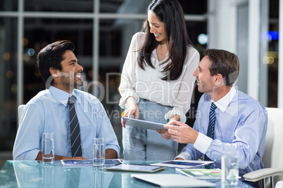 Businesswoman discussing with colleagues over digital tablet