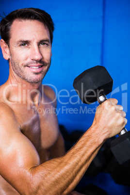 Portrait of smiling athlete lifting dumbbell