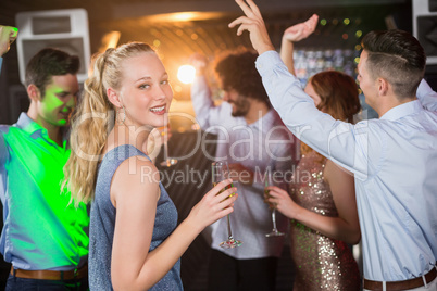 Woman holding glass of champagne while dancing with friends