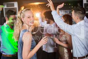 Woman holding glass of champagne while dancing with friends