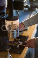 Waiter holding portafilter filled with ground coffee