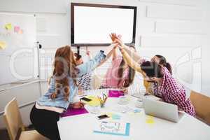 Business people giving high-five together in meeting at creative office