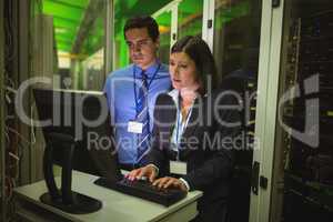 Technicians working on personal computer while analyzing server