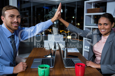 Business executives giving high fives while working in office