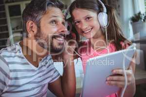 Father and daughter listening music on digital tablet