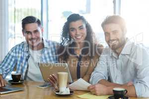 Smiling friends using digital tablet and laptop in cafÃ?Â©