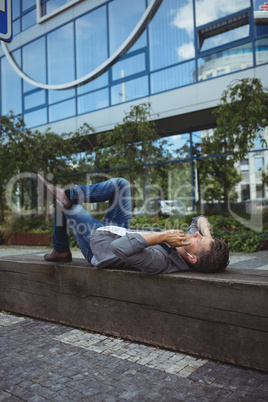 Business executive lying on wood and listening music