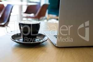 Close -up of cup of coffee and laptop on table