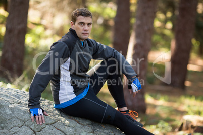 Male biker relaxing on rock in forest