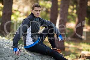 Male biker relaxing on rock in forest