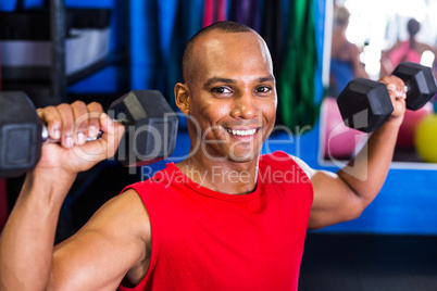 Portrait of happy man lifting dumbbell in gym