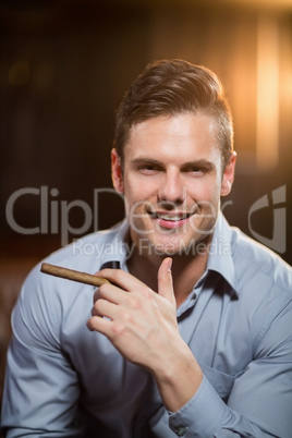 Smiling man holding a cigar in bar