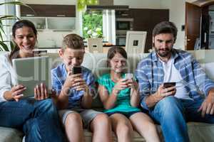 Family using laptop and mobile phone in living room