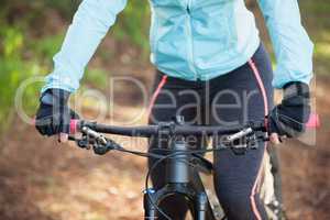 Mid section of female mountain biker riding bicycle in the forest