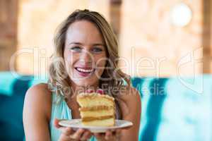 Smiling woman holding pastry on plate