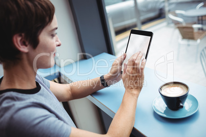 Businesswoman using digital tablet while having coffee