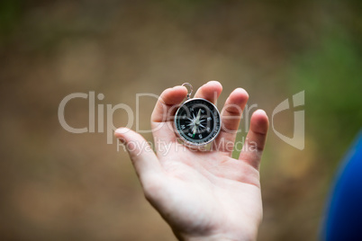 Hand holding compass in forest