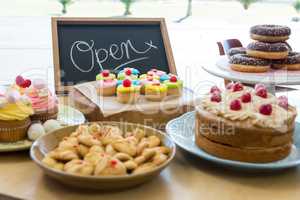 Close-up of various sweet foods on table with open signboard