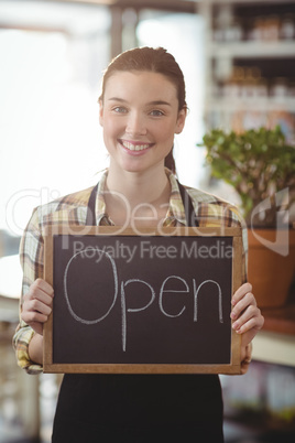 Portrait of waitress showing chalkboard with open sign