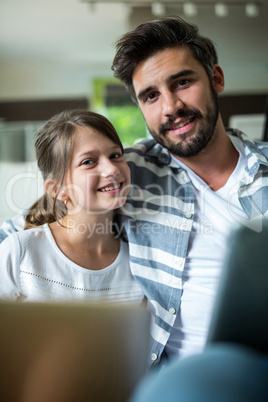 Portrait of father and daughter using laptop and digital tablet in the living room