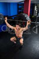 shirtless man lifting barbell in gym