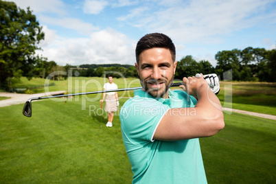 Man standing with golf club in golf course