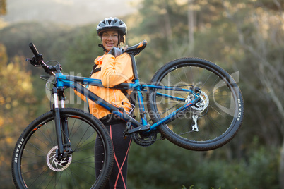 Female biker carrying mountain bike