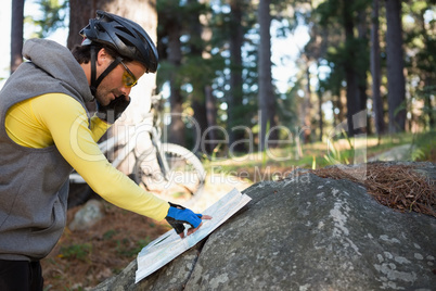 Mountain biker talking mobile phone while looking at map