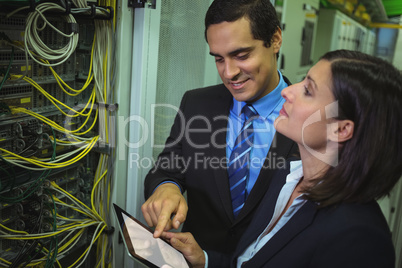 Technicians using digital tablet while analyzing server
