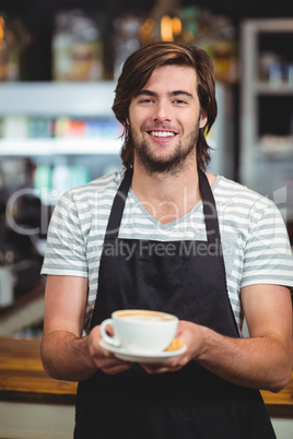 Portrait of waiter offering a cup of coffee