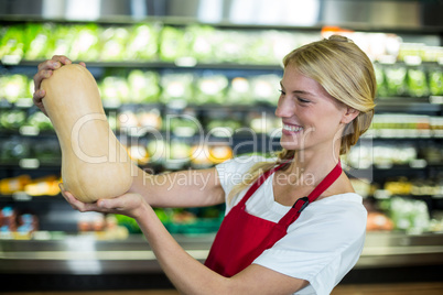 Smiling female staff holding a vegetable in organic section