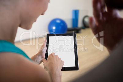 Woman showing digital tablet to fitness trainer