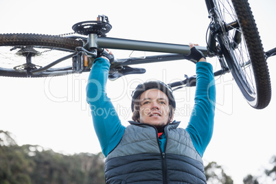 Male mountain biker carrying bicycle in the forest