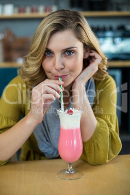 Portrait of woman drinking milkshake with a straw