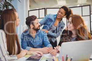 Businessman with happy female coworkers at desk