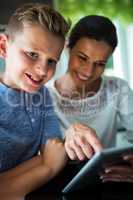 Mother and son using digital tablet in the living room