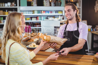 Waiter giving bread roll to customer at counter