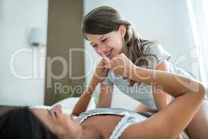 Mother and daughter playing on bed