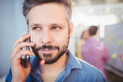 Close-up of businessman listening to cellphone at creative office