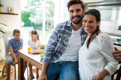 Portrait of couple sitting with arm around on dining table