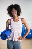 Portrait of smiling woman holding exercise mat