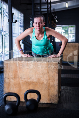 Portrait of young athlete using wooden cube in gym