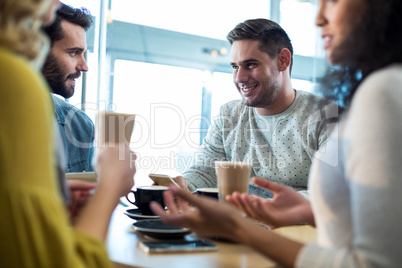 Smiling friends having a cup of coffee and cold coffee in cafÃ?Â©